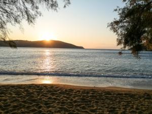 a beach with the sun setting over the water at Alexandros by the Beach - Serifos in Livadakia