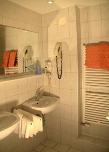 ein Badezimmer mit einem Waschbecken und einem Telefon an der Wand in der Unterkunft Best Breakfast - Hotel Justina in Bad Wörishofen