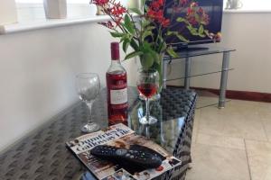 a table with a bottle of wine and a glass at Castlemoor Holiday Cottage, Mull of Galloway in Drummore