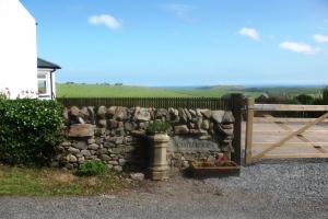 a stone wall with a wooden gate and a fence at Castlemoor Holiday Cottage, Mull of Galloway in Drummore