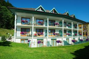 ein großes weißes Gebäude mit Blumen auf den Balkonen in der Unterkunft Seehotel Princes in Sankt Kanzian am Klopeiner See