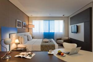 a hotel room with a bed and a desk with a laptop at Intercity Salvador in Salvador