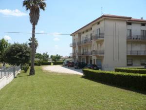 a building with a palm tree in front of a yard at Appartamento CUPRA in Cupra Marittima
