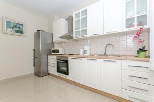 a kitchen with white cabinets and a stainless steel refrigerator at Apartments Ivan in Prizba