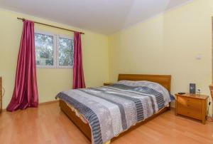 a bedroom with a bed and a window with red curtains at Apartments Ivan in Prizba +30 photos