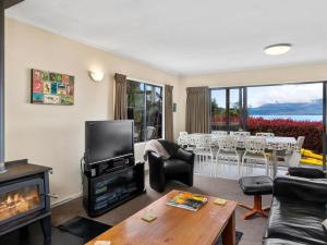 sala de estar con TV y chimenea en Lakeside Escape - Lake Tarawera Holiday Home, en Lake Tarawera