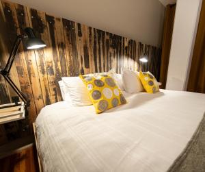 a bedroom with a white bed with yellow pillows at Don Jacinto Stay&Sip in Mexico City