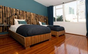 2 camas en un dormitorio con paredes azules y suelo de madera en Don Jacinto Stay&Sip en Ciudad de México