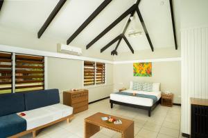 Plantation Island Resort في Malolo Lailai: غرفة معيشة مع سرير وأريكة