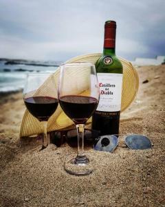 Una botella de vino y dos copas en la playa en Casa de Playa Arica, en Lurín