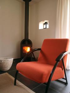 an orange chair in a room with a fireplace at Boerderij het Reestdal in Linde