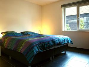 a bedroom with a bed with a colorful comforter and a window at Boerderij het Reestdal in Linde
