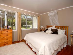 a bedroom with a bed and a dresser and windows at Hibiscus - Matapouri Holiday Home in Matapouri