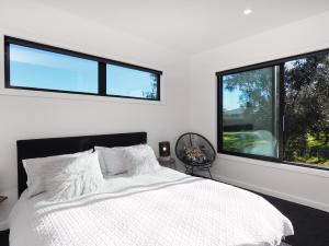 una camera con un letto bianco e due finestre di Pinot Longbox - Martinborough Holiday Home a Martinborough