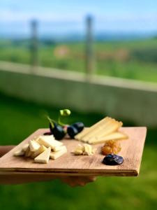 a person holding a cutting board with cheese and olives at Refúgio Pé da Serra - Chalés in São Roque de Minas