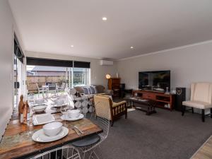 a living room with a table with chairs and a television at First Choice in Mangawhai - Mangawhai Holiday Home in Mangawhai