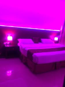 een slaapkamer met een bed met roze verlichting bij أضواء رفا 2 in Al Kharj