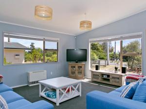 a living room with a blue couch and a tv at Taruna - Tauranga Taupo Holiday Home in Kuratau