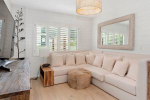 Sala de estar blanca con sofá blanco y espejo en Kiwi Kuta with direct beach access -Matarangi Home en Matarangi