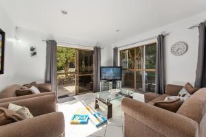 a living room with two couches and a tv at Sandcastles on Tay - Mt Maunganui Holiday Home in Mount Maunganui