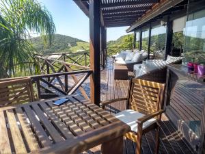 una terrazza in legno con panca e sedie. di La Roca House a Praia do Rosa