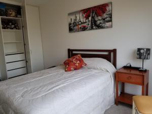 Un dormitorio con una cama con una almohada roja. en Dormitorio Privado dentro de Departamento en Lima