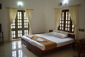 1 Schlafzimmer mit einem großen Bett und 2 Fenstern in der Unterkunft Oriole Homestay in Thekkady