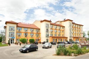 eine Gruppe von Gebäuden mit Autos auf einem Parkplatz in der Unterkunft Airport Hotel Budapest in Vecsés