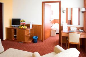 a hotel room with a desk and a television in a room at Airport Hotel Budapest in Vecsés