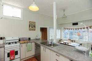 uma cozinha com um lavatório e um fogão forno superior em Puriri Downtown Villa - Napier Holiday Home em Napier