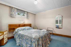 a bedroom with a bed and a dresser and a mirror at Leica Stay - Napier Holiday Home in Napier