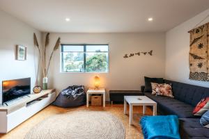 uma sala de estar com um sofá azul e uma televisão em Treetop Retreat - Onetangi Holiday Home em Onetangi