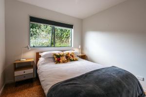 a bedroom with a bed with a large window at Treetop Retreat - Onetangi Holiday Home in Onetangi