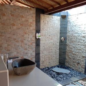 a bathroom with a sink and a stone wall at Pondok Lembongan in Nusa Lembongan