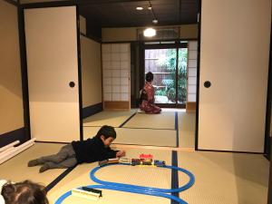 un joven tirado en el suelo jugando con un tren de juguete en 京ﾉ家 五条西洞院 en Kioto