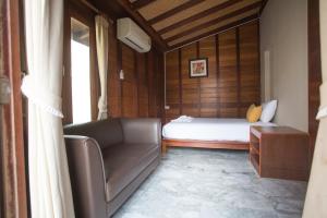 ein Schlafzimmer mit einem Bett, einem Sofa und einem Fenster in der Unterkunft 100 Islands Resort & Spa in Surat Thani