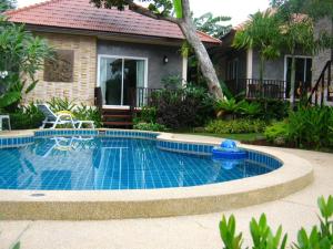 a swimming pool in front of a house at Pennapa Chalet in Chalong