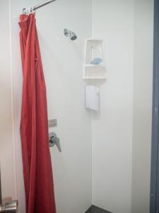 a shower with a red curtain in a bathroom at Urbanz in Christchurch