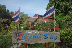 una señal frente a un complejo de la bahía local con dos banderas en Koh Jum Coral Bay Resort, en Ko Jum