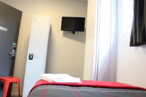 a bedroom with a bed with a red blanket and a tv at Urbanz in Christchurch
