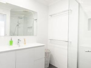a white bathroom with a sink and a shower at Tiro Moana in Forster +4 photos