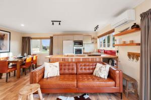 a living room with a brown leather couch in a kitchen at The Purple House - Ohakune Home with Spa Pool in Ohakune
