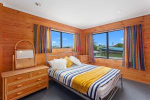 a bedroom with a bed with a dresser and a mirror at Ohope Sunshine Escape - Ohope Holiday Home in Ohope Beach