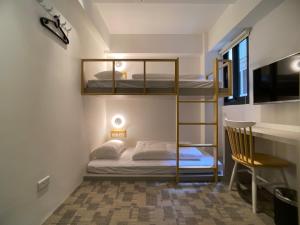 Letto a castello in camera con sedia e scrivania di We Come Hostel a Taipei