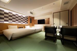 a bedroom with a bed and a tv and chairs at PROSTYLE RYOKAN TOKYO ASAKUSA in Tokyo