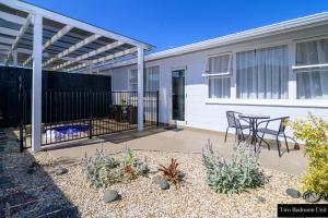 un patio con tavolo e sedie di fronte a un edificio di Thermal Oak Motel a Rotorua