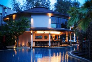 a building with a swimming pool in front of it at Tara Mantra Cha-Am Resort in Cha Am