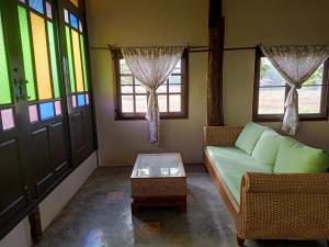a living room with a couch and a table and windows at Ing Doi Guest House in Pai