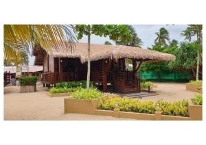 a hut with a straw roof and some plants at Nilaveli Beach Resort - Level 1 Certified in Nilaveli