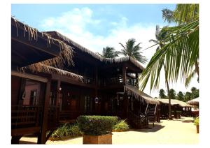 a building with straw umbrellas and palm trees at Nilaveli Beach Resort - Level 1 Certified in Nilaveli
